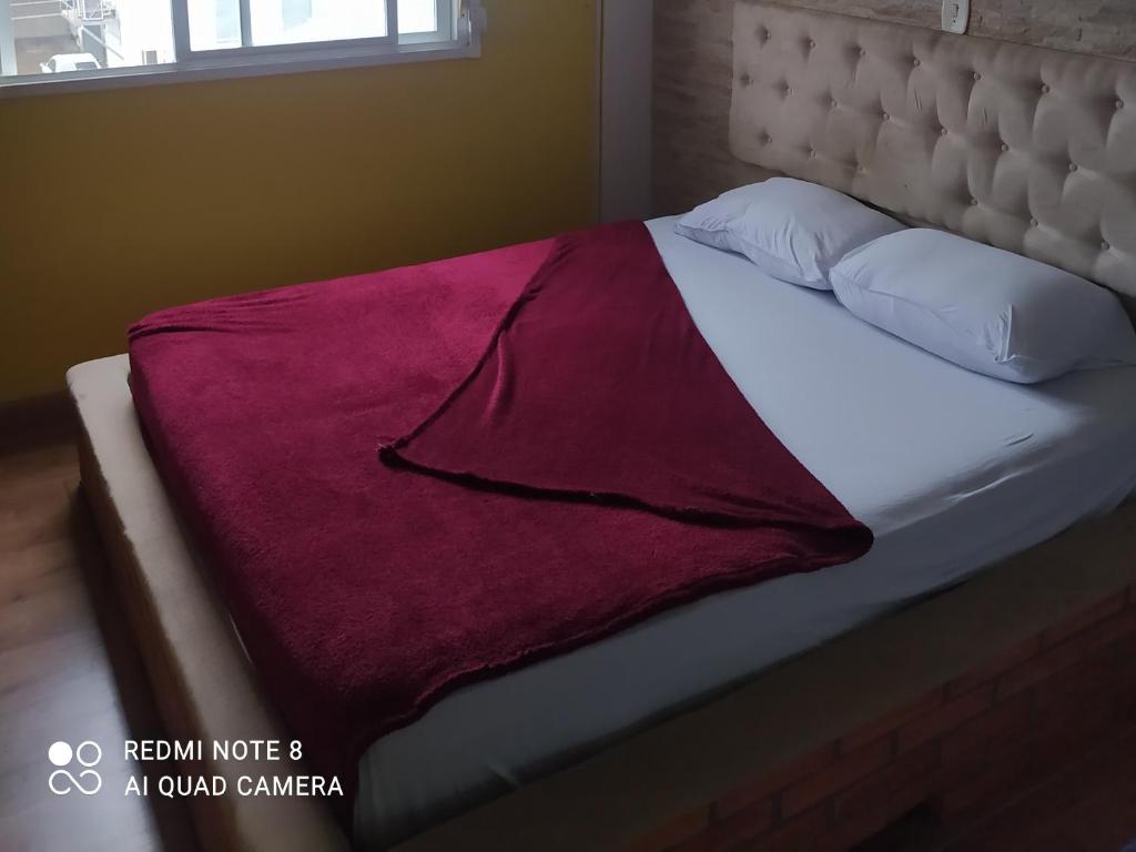 een bed met een rode deken erop bij Flat central dois quartos in Guaporé