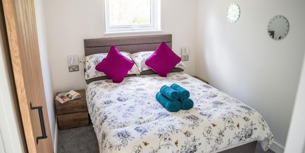 a bedroom with a bed with pink and purple pillows at Back to Nature Squirrels Lodge 1 bedroom lodge in South Molton