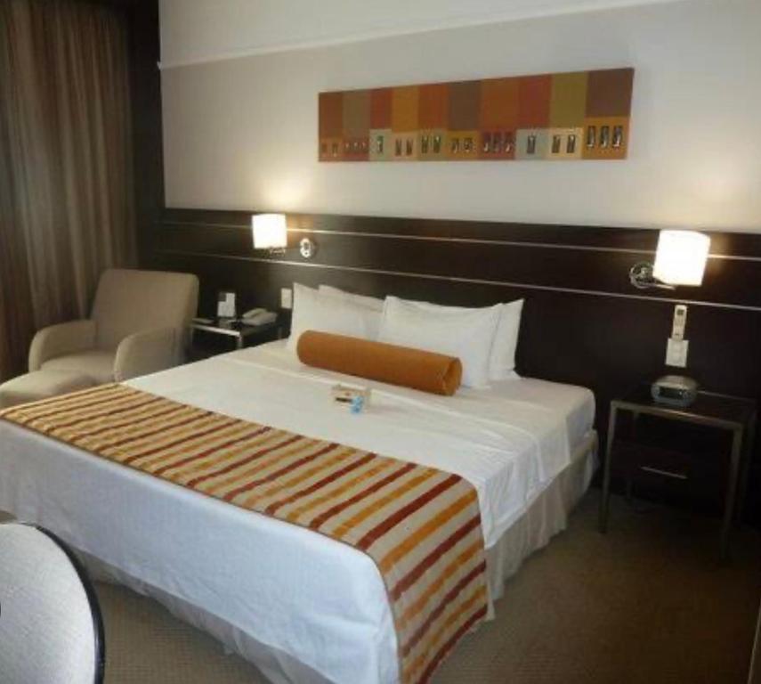 una habitación de hotel con una cama grande y una silla en Hotel de luxo BH, en Belo Horizonte
