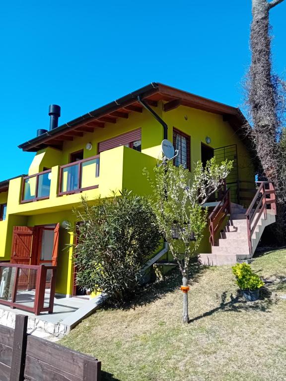 una casa amarilla y verde con un árbol frente a Pineta 4 y 7 en Villa Gesell