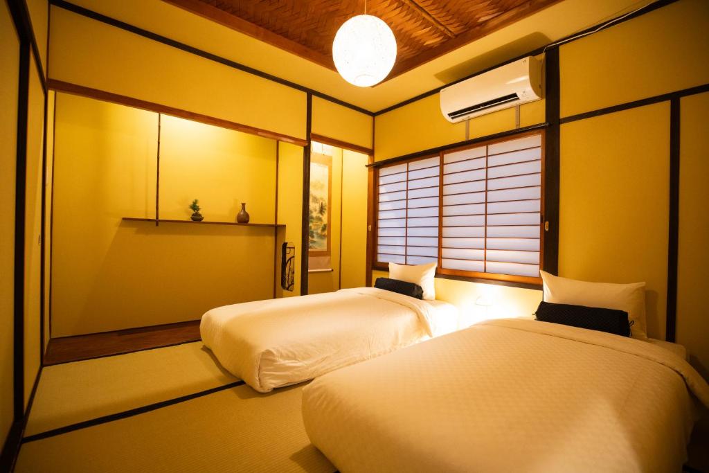 Duas camas num quarto com paredes amarelas em 東雲庵/shinonomean em Quioto