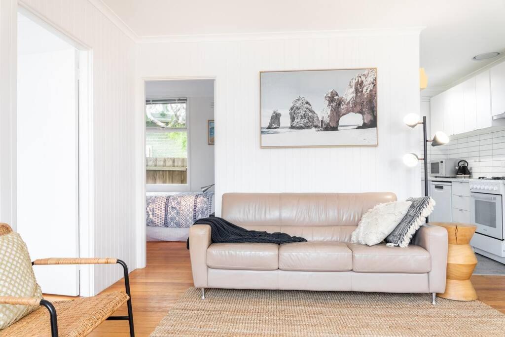 a white living room with a couch and a kitchen at Beachside Gem in Ocean Grove in Ocean Grove