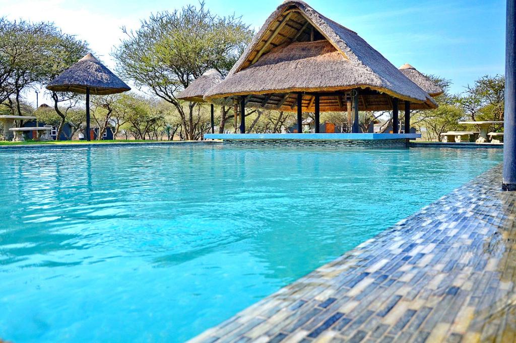 a swimming pool with a gazebo and blue water at Bradbury Game Lodge and Function Venue in Polokwane