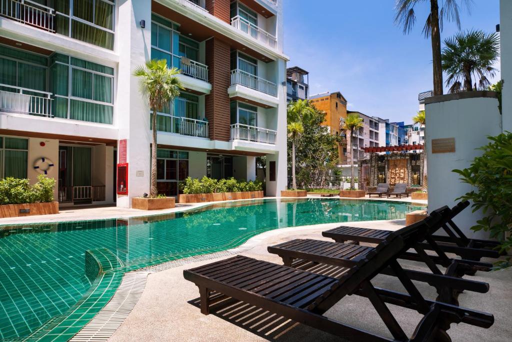 a swimming pool with two benches in a building at iCheck inn Residences Patong in Patong Beach