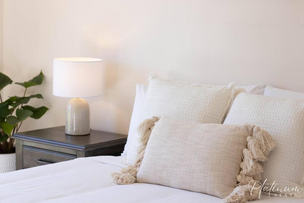 ein weißes Bett mit einem Kissen und einer Lampe auf dem Tisch in der Unterkunft Glenare on Read in Horsham