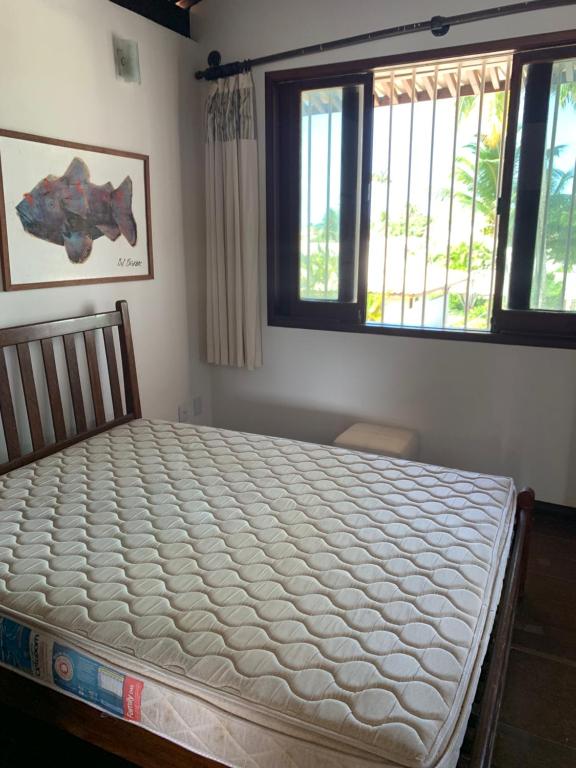 a bed in a room with two windows at Linda Casa na Penha ! in Vera Cruz de Itaparica