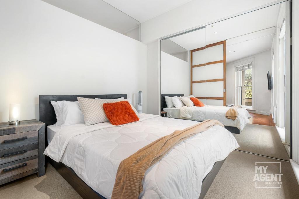 a bedroom with two beds and a mirror at Melbourne Bourke Street Bliss in Melbourne