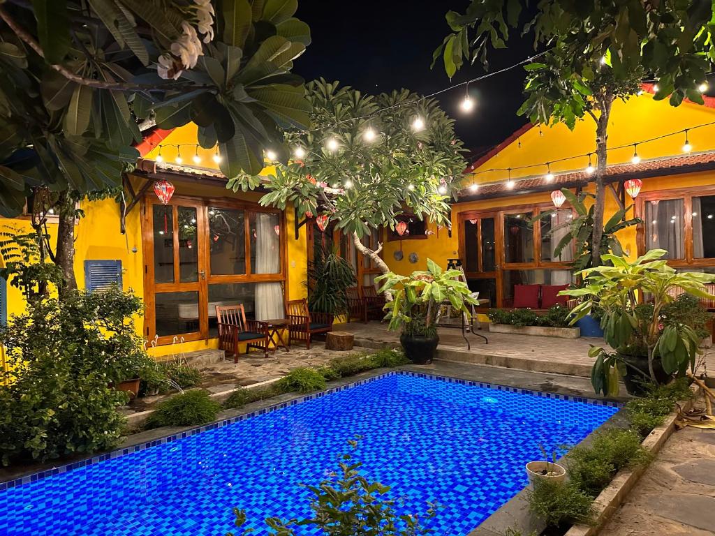 a swimming pool in front of a house at night at La Belle Anbang Homestay in Hoi An