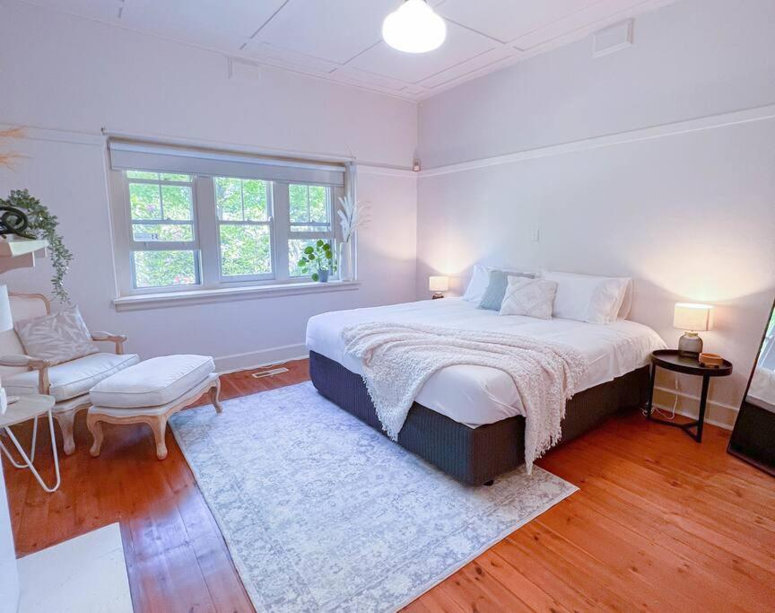 1 dormitorio blanco con 1 cama y 1 silla en • Parkside • Spacious central family retreat en Alfredton