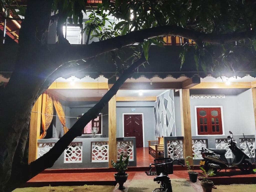 a house with a tree in front of it at Enoch Guest House in Mannar