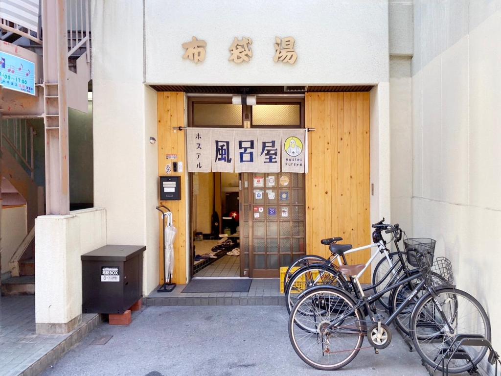 dos bicicletas estacionadas frente a un edificio en Hostel Furoya en Osaka