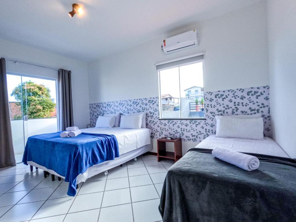 a bedroom with two beds and a window at Pousada Jardins - Mar Grande in Vera Cruz de Itaparica