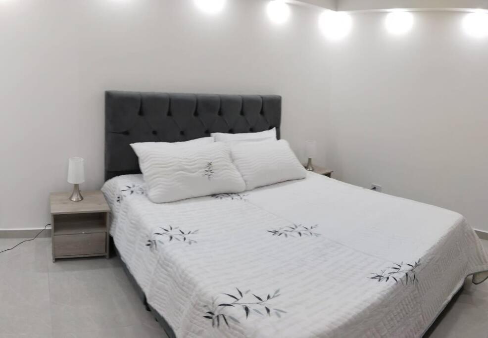 a bedroom with a white bed with a black headboard at Encantador Apto Con Aire in Neiva