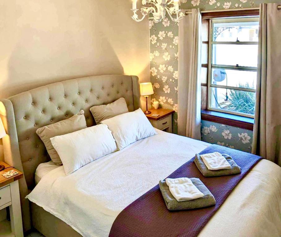 Inglenook Cottage في مونتا: غرفة نوم بها سرير عليه منشفتان