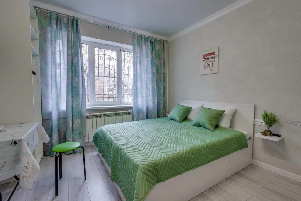 een slaapkamer met een bed met groene lakens en een raam bij Asaapart Mega Studio 2 in Alma-Ata