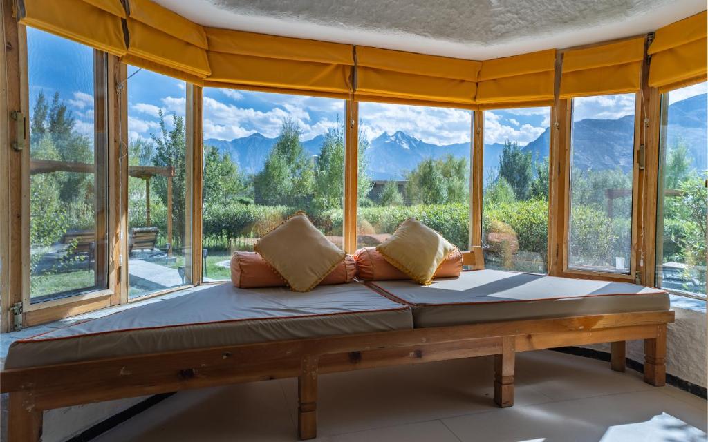 a bed in a room with a large window at Lchang Nang Retreat-THE HOUSE OF TREES in Nubra