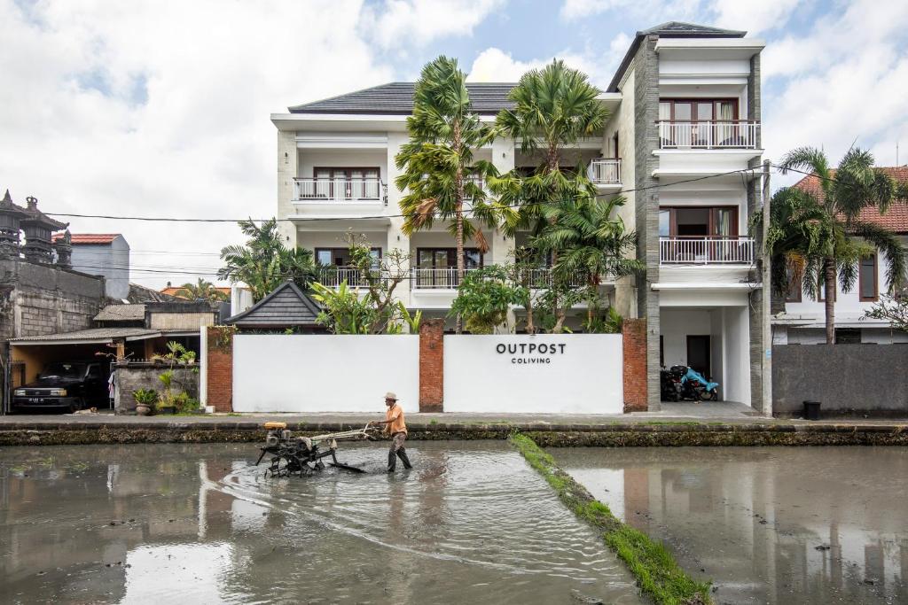 a man walks through a flooded street in front of a building at Outpost Canggu in Canggu