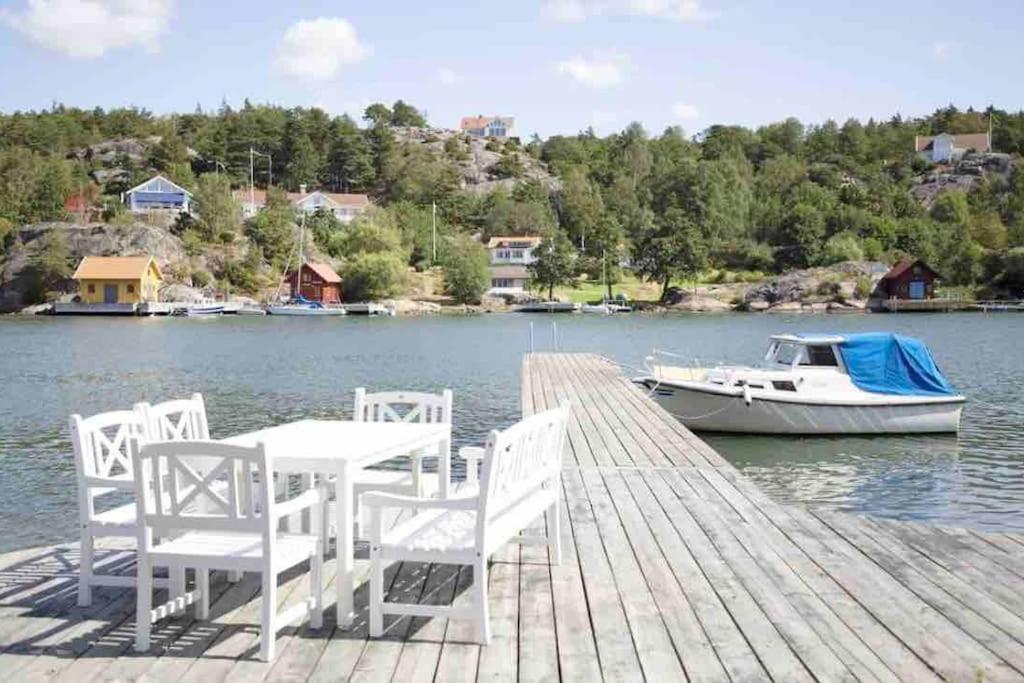 una mesa y sillas en un muelle con un barco en SeaSide, en Hjälteby