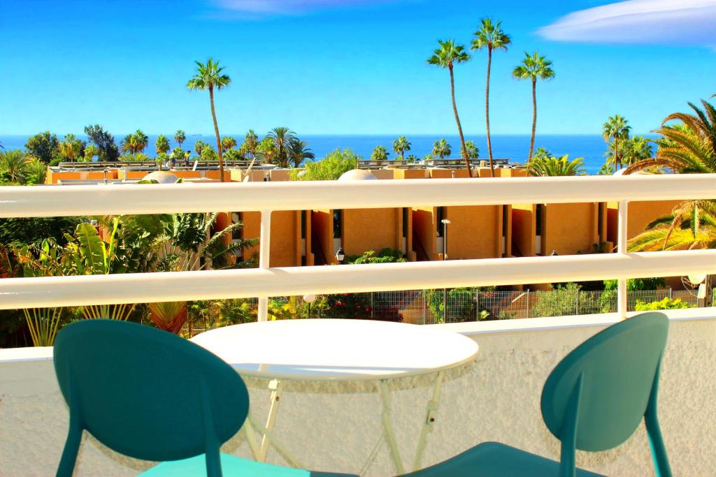 een tafel en stoelen op een balkon met uitzicht op de oceaan bij Borinquen Vista Mar in Playa de las Americas