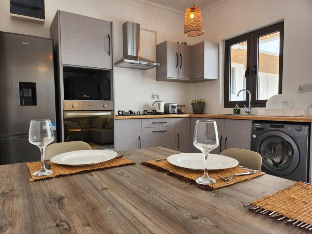 a kitchen with a wooden table with two wine glasses on it at Appart T2 piscine et fitness in Grand Baie