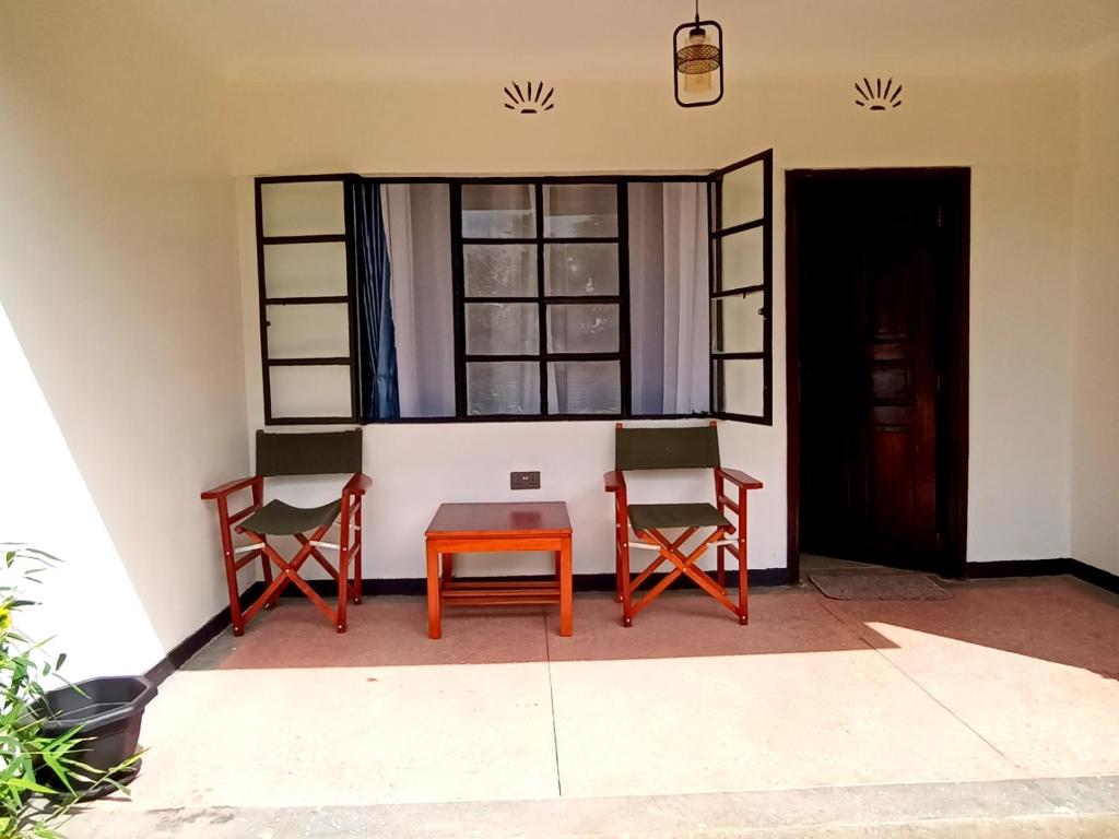 - deux chaises et une table dans une chambre avec fenêtre dans l'établissement Riverside 001, à Nanyuki