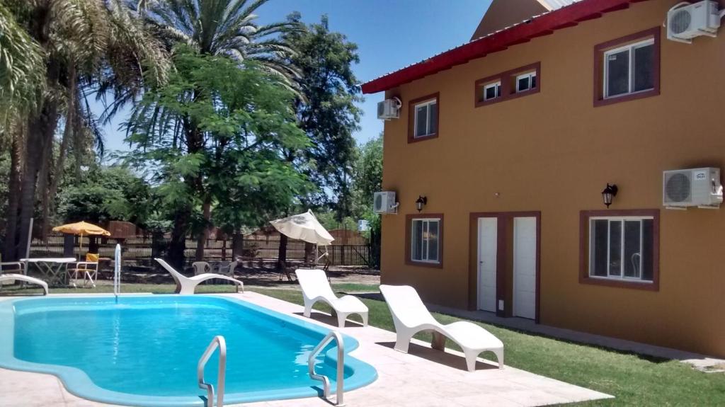 a villa with a swimming pool in front of a house at Cabañas Ensueño del Lago in Termas de Río Hondo