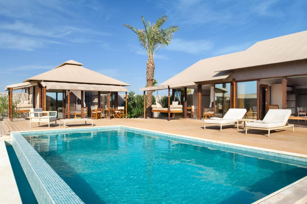 a villa with a swimming pool and a resort at The Outpost Al Barari in Mesaieed