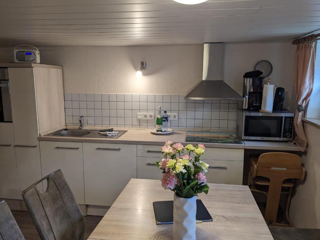 a kitchen with a table with a vase of flowers on it at Huus Meta in Krummhörn