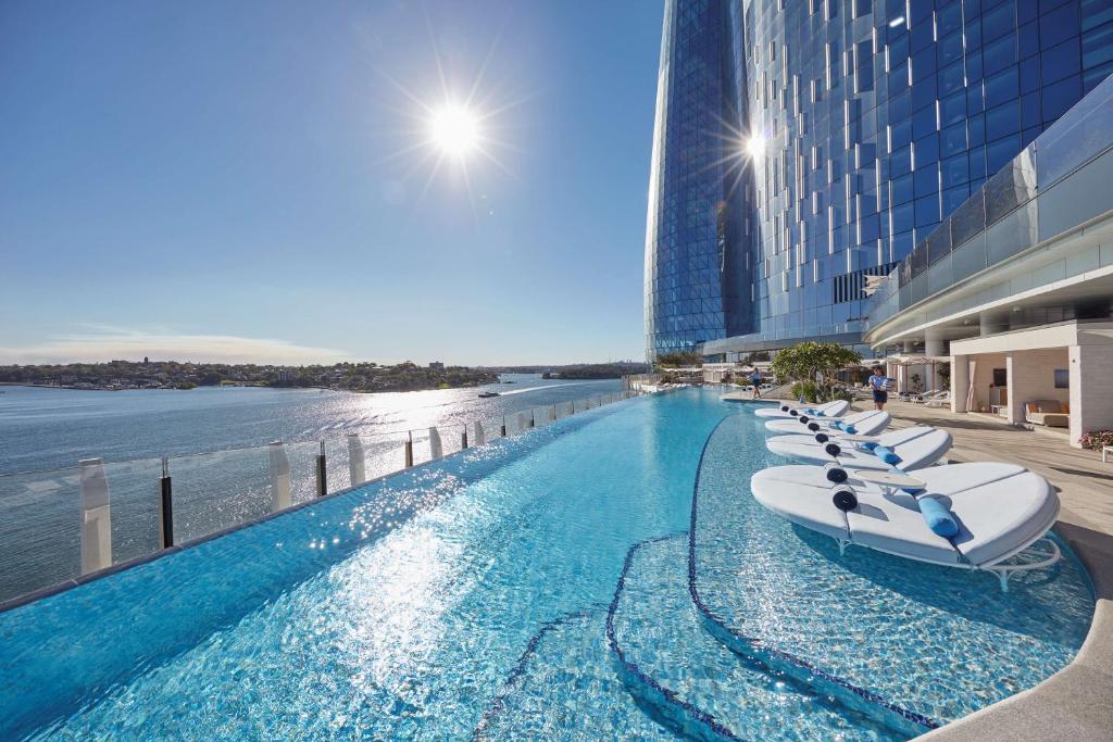 a hotel swimming pool with a row of lounge chairs at Crown Towers Sydney in Sydney