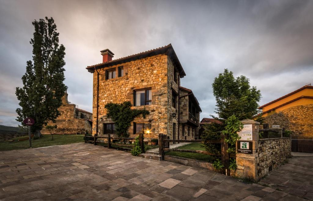 una vieja casa de piedra con una valla delante de ella en Centro de Turismo Rural La Coruja del Ebro, en Valderredible