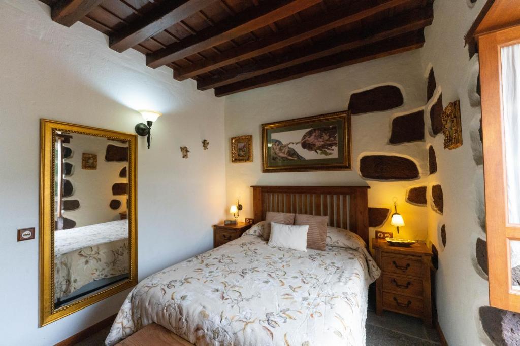 a bedroom with a bed and a mirror at Ancient Historical House in Santa Lucía