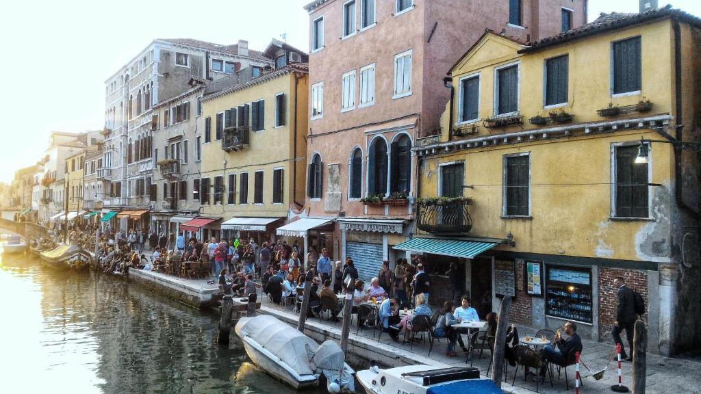 a group of people sitting at tables next to a canal at Ca'Rosa in Venice