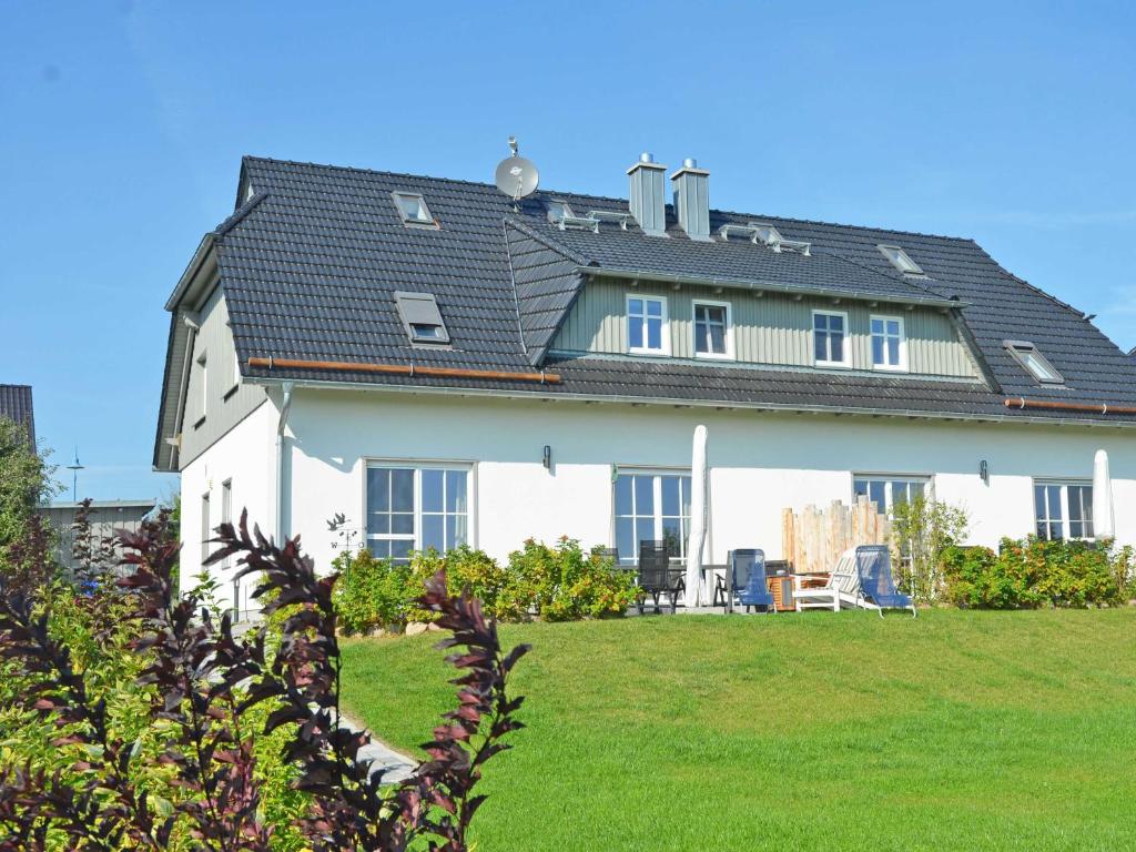 ein großes weißes Haus mit schwarzem Dach in der Unterkunft Haus Mönchgut - Haushälfte 1 "Feuerstein" in Alt Reddevitz
