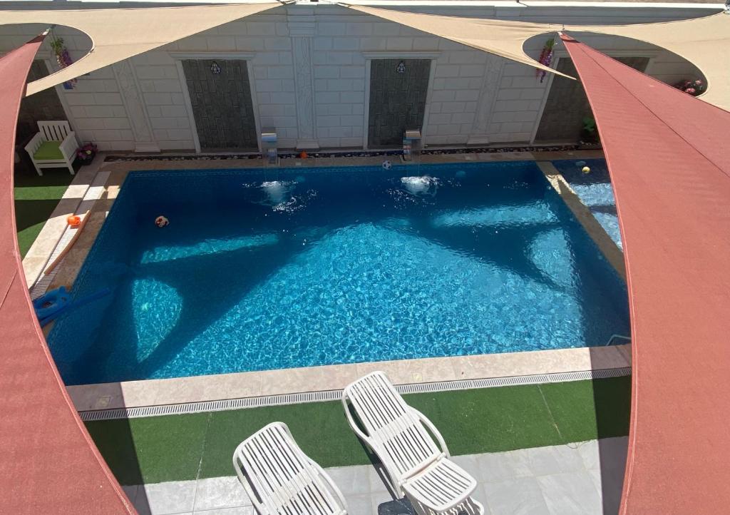 a swimming pool with two chairs next to a building at شاليه ڤيو VIEW Chalet in Sowayma