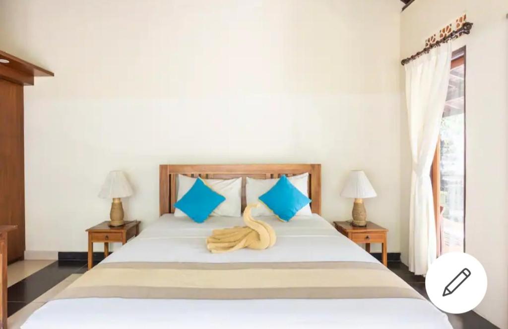 烏布的住宿－烏布阿雷之家旅館，一间卧室配有一张带蓝色枕头的大床