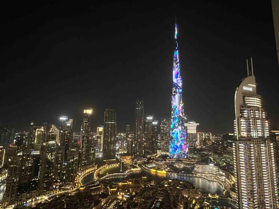 einen beleuchteten Turm in einer Stadt in der Nacht in der Unterkunft 3BR, Burj Khalifa,Fountain48 in Dubai
