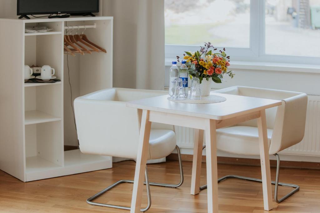 een witte tafel en stoelen met een vaas met bloemen erop bij Spadrops in Ikšķile