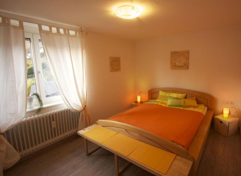 a bedroom with an orange bed and a window at Haus Rebberg in Wolfach