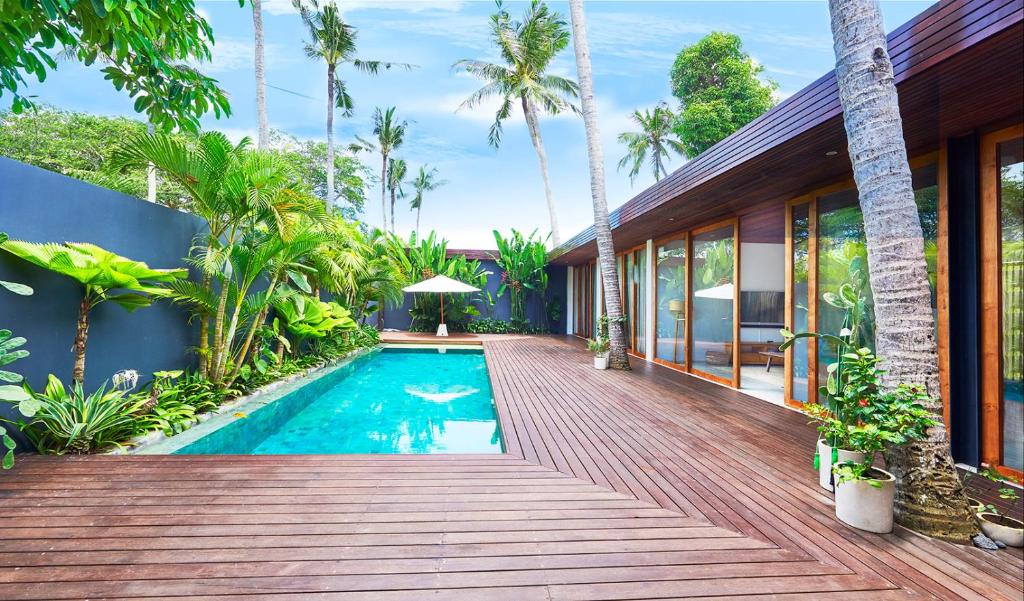 a house with a swimming pool and a wooden deck at Amazing 3BDR-Villa Canggu/Seseh 2min walk to Beach in Canggu