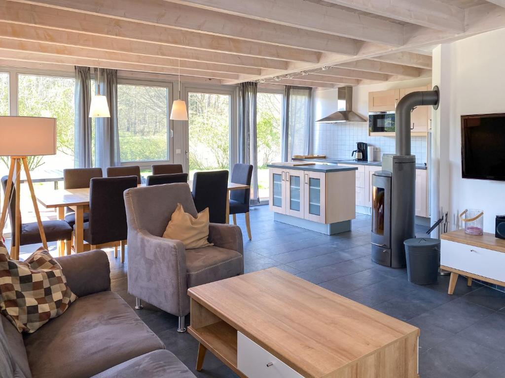 sala de estar con sofá, mesa y cocina en Ferienhaus Wiesengeflüster W10 - mit Sauna, Kamin und Garten, en Röbel