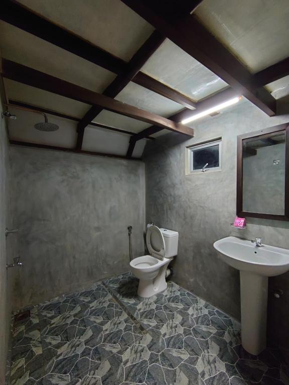 a bathroom with a toilet and a sink at Rainforest cabin in Deniyaya