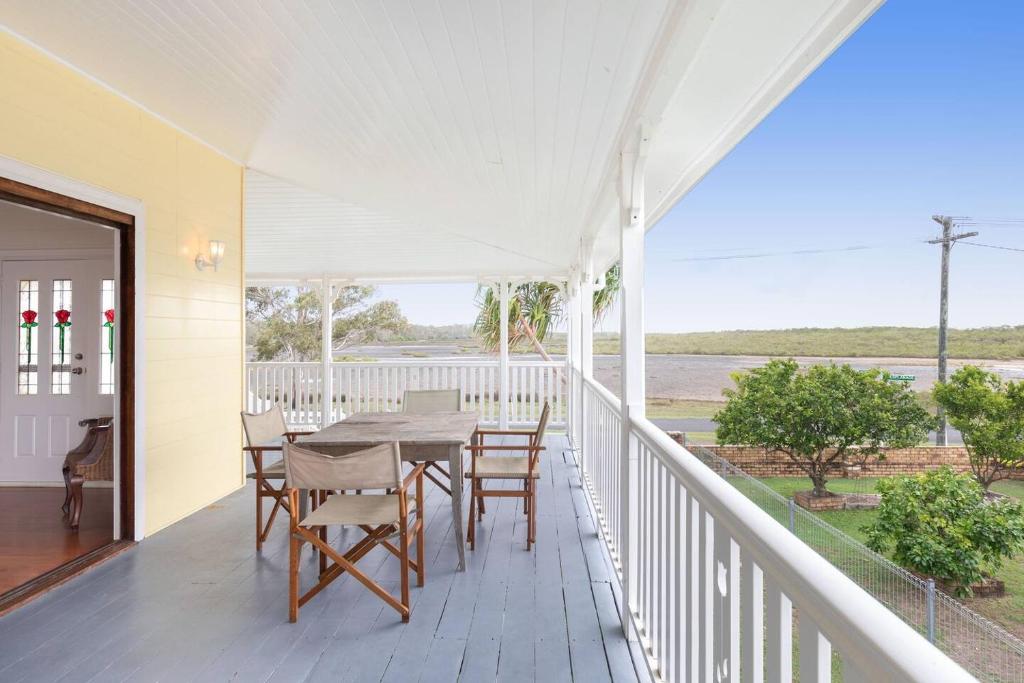een witte veranda met een tafel en stoelen erop bij Coastal Queenslander with Fraser Island Views in Boonooroo