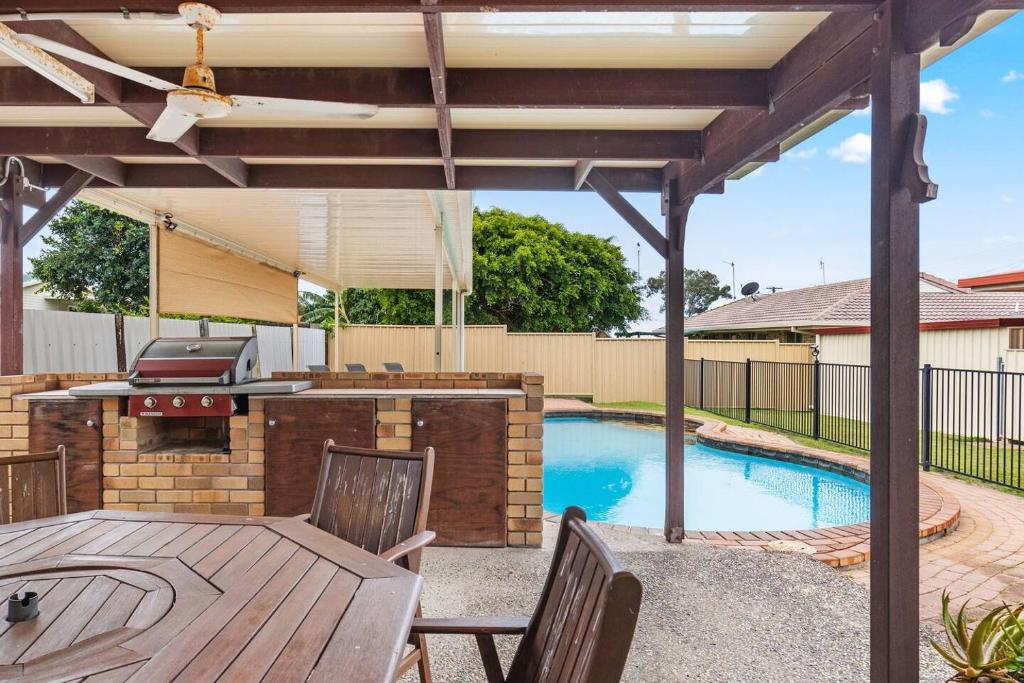 um pátio com uma mesa, comodidades para churrascos e uma piscina em 'The Aussie Classic' Poolside Living by the Marina em Urangan