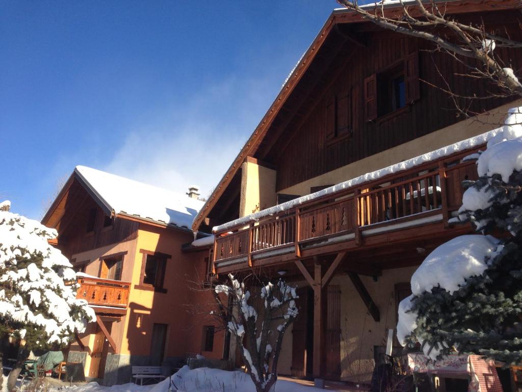 uma grande casa de madeira com uma varanda na neve em Chalets La Caillaude em La Salle Les Alpes