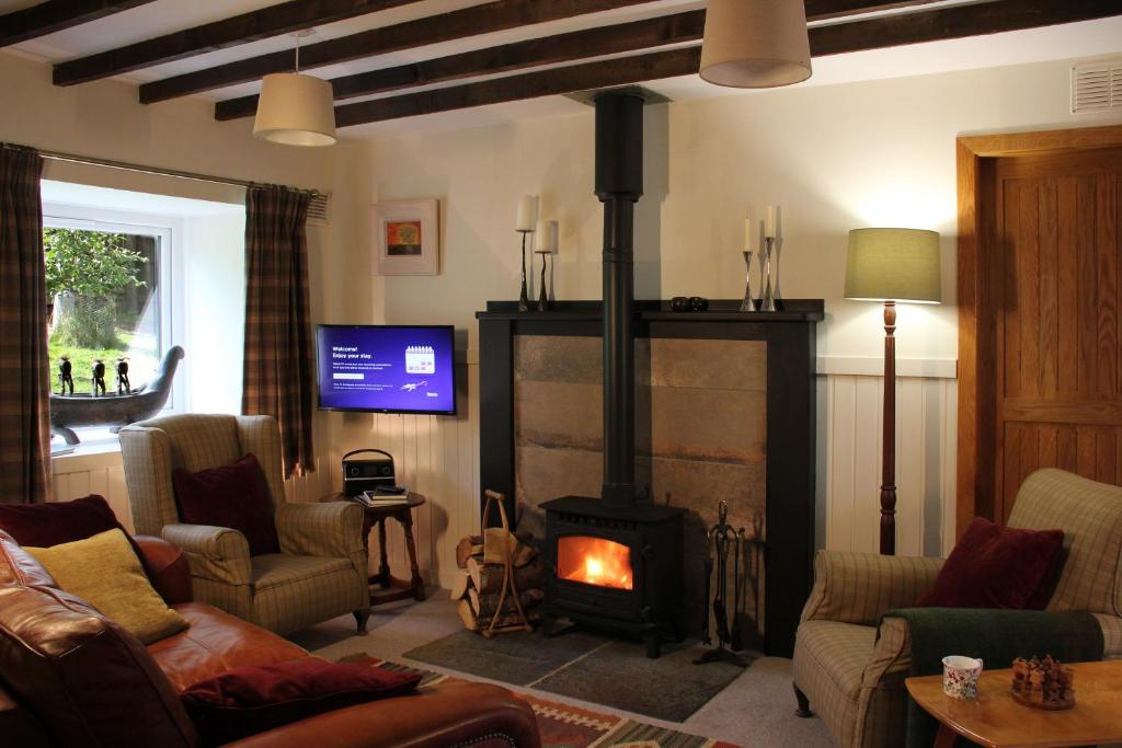 a living room with a fireplace and a tv at Smithy Cottage in Strathdon