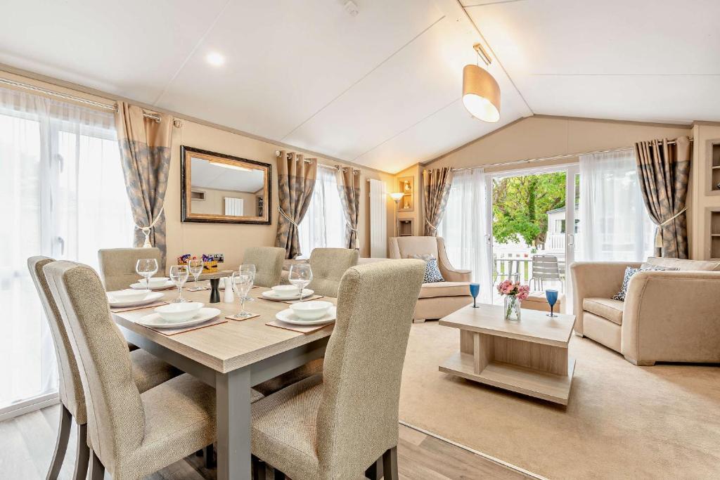 a dining room and living room with a table and chairs at Artisan Lodge Shorefield Country Park Downton Lymington in Lymington