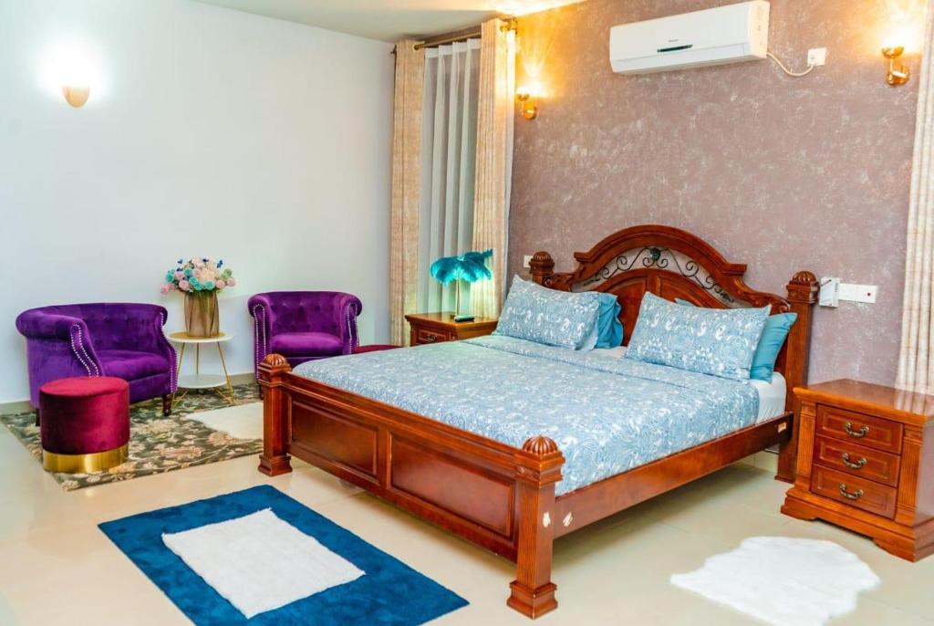 ein Schlafzimmer mit einem Bett und zwei lila Stühlen in der Unterkunft Home away from home, 5 Bedroom Villa, Bustani Close, Nyali Beach in Mombasa