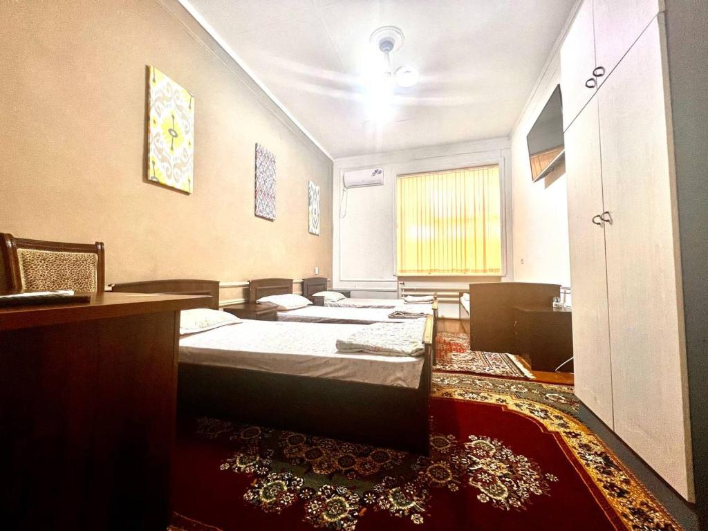 een kamer met drie bedden in een kamer met een tapijt bij Hello Hostel in Samarkand