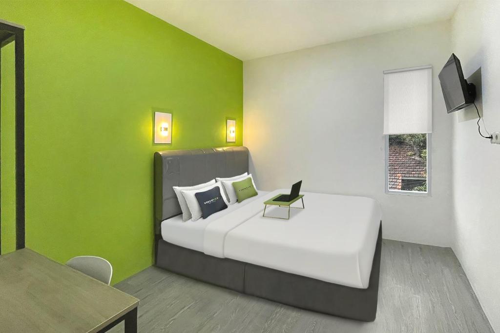 a bedroom with a white bed with a green wall at Urbanview Syariah Don Juan Pondok Gede in Warungsergon