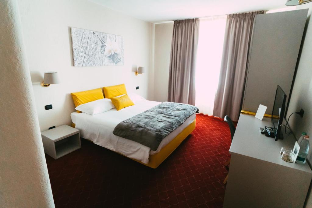 um quarto de hotel com uma cama com almofadas amarelas em Essenza Hotel em Verrès